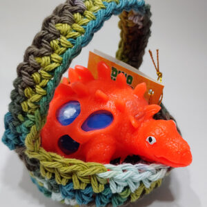 Orange dino in hand-crocheted gift basket